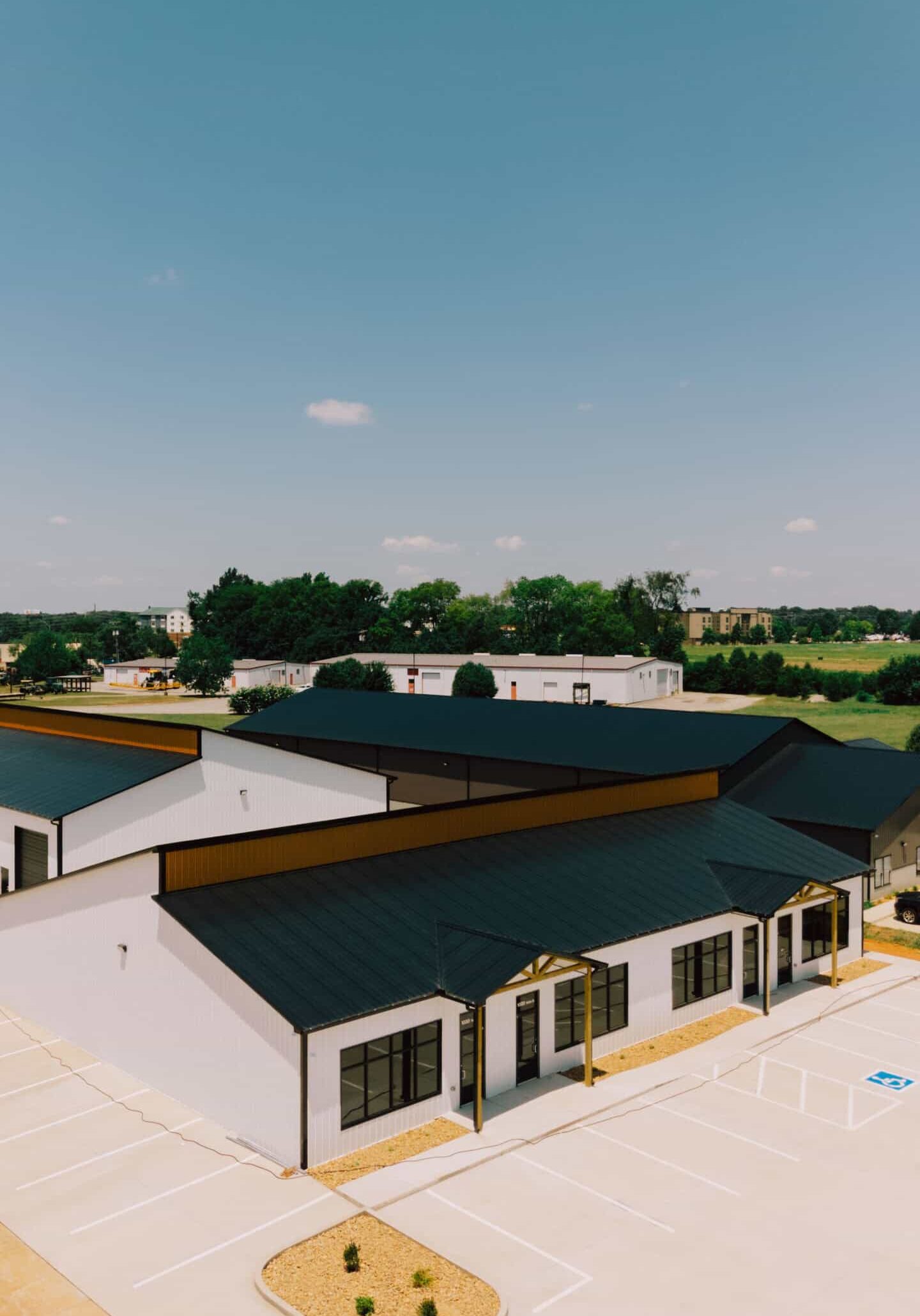 Bright, modern commercial building with black metal roof, white exterior walls, large windows, and parking lot, showcasing WW Buildings' expertise in prefab steel structures for businesses.